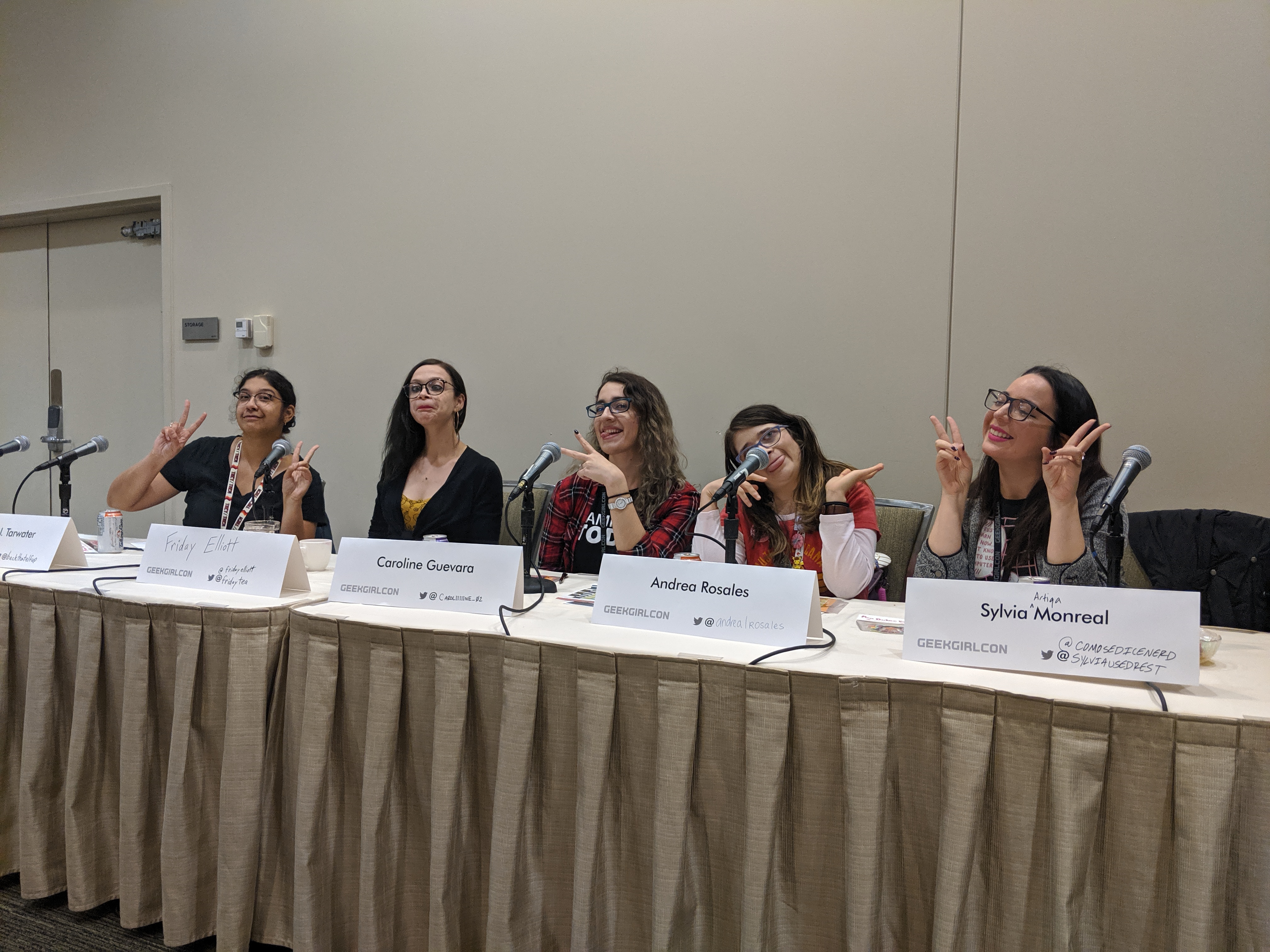 5 people sit at a long table making silly poses and faces.
