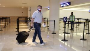 Ted Cruz fleeing Texas for a Cancun vacation during the deadly 2021 winter storm, looking baffled and wearing a Texas flag mask