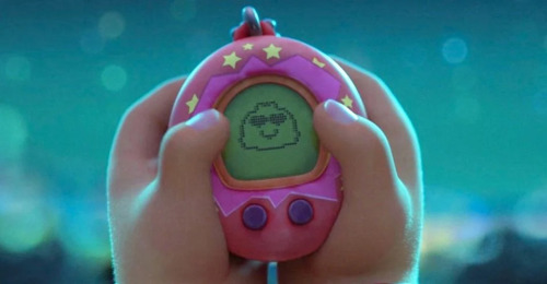 Mei's Tamagotchi beams heart eyes back at her as she holds it in her hands.